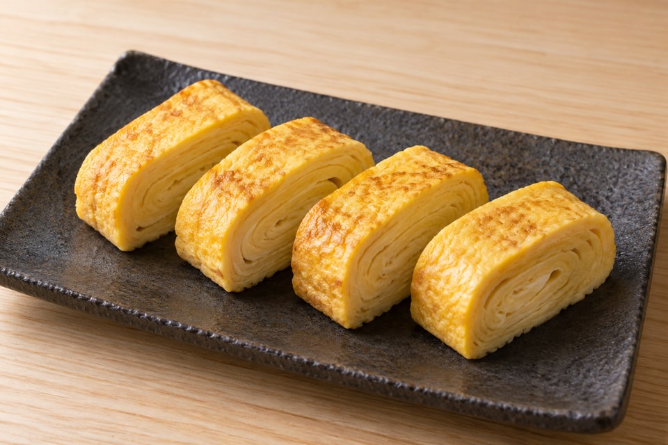 AI illustration of tender golden tamagoyaki slices showing continuous cooked egg layers, without rice. — AI recipe illustration